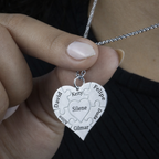 Colar_Coracao_de_Mae_prata_personalizado_com_nomes_gravados_modelo_segurando_o_pingente_para_destacar_os_detalhes