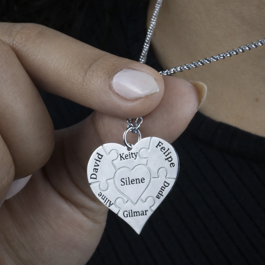 Colar_Coracao_de_Mae_prata_personalizado_com_nomes_gravados_modelo_segurando_o_pingente_para_destacar_os_detalhes