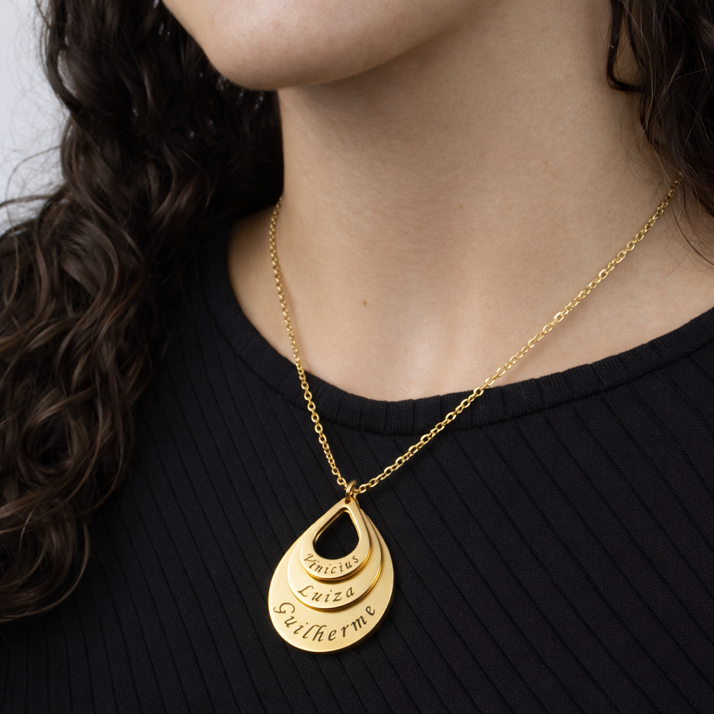 Colar_Gota_de_Amor_dourado_com_nomes_gravados_modelo_usando_o_pingente_sobre_blusa_preta