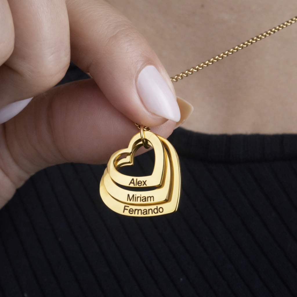 Colar_Coracoes_Crescentes_dourado_personalizado_com_nomes_modelo_segurando_o_pingente_para_destacar_os_detalhes_da_gravacao