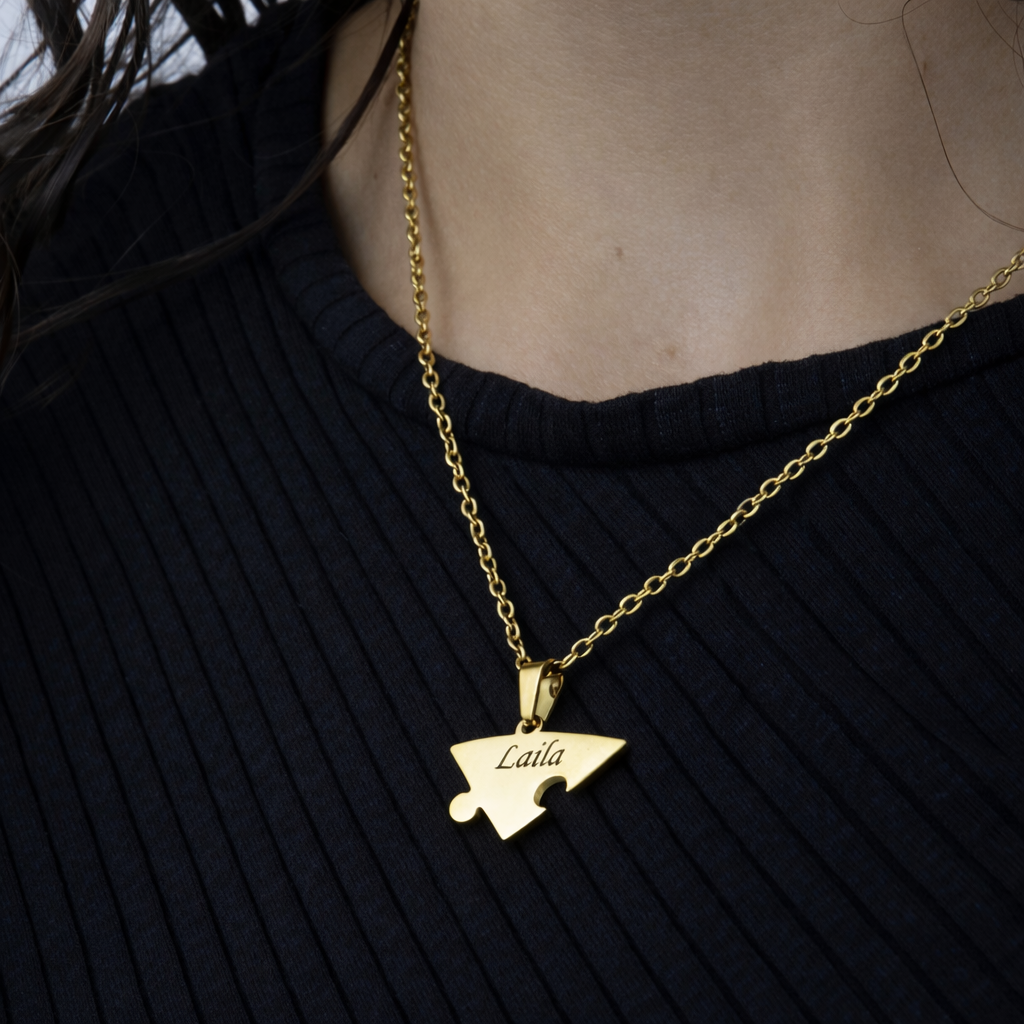 Colar dourado com pingente em formato de peça de quebra-cabeça com o nome Laila gravado sendo usado no pescoço