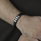 Close_no_pulso_com_pulseira_de_couro_preta_e_gravacao_personalizada_em_aco_mostrando_ajuste_e_detalhe