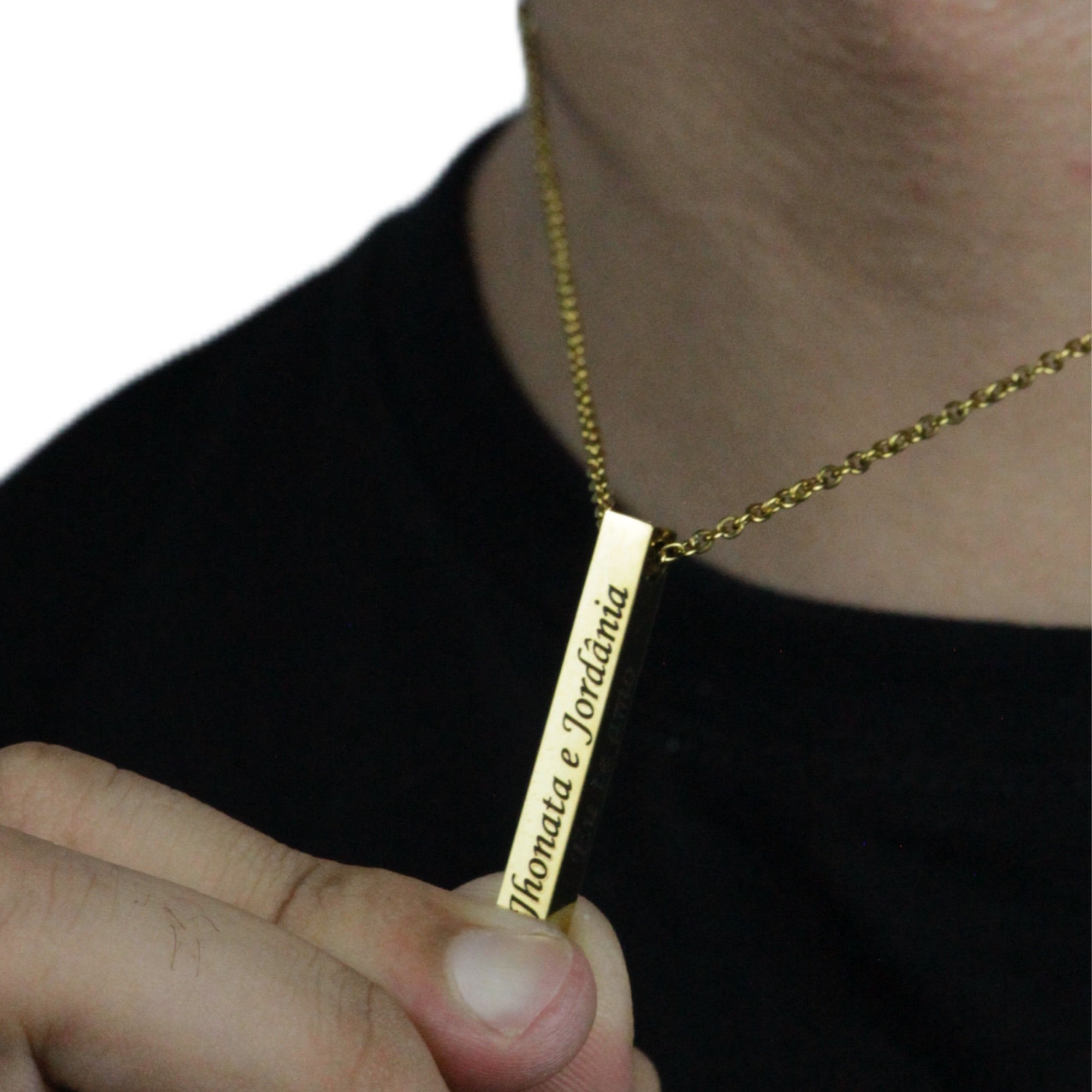 Colar_4D_dourado_com_nomes_gravados_sendo_segurado_em_close_pelo_modelo