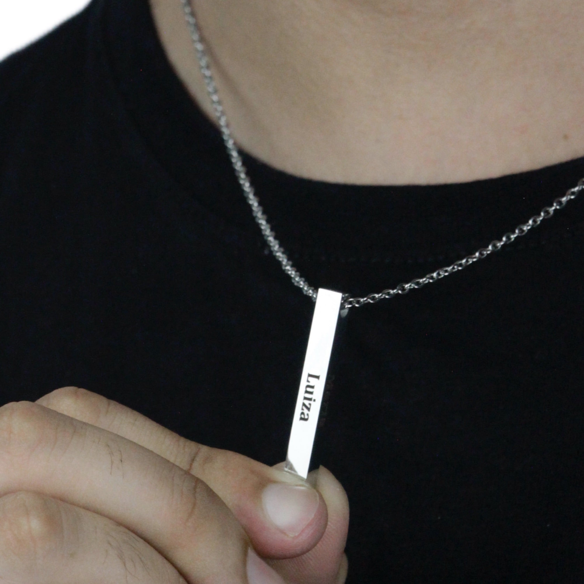 Colar_4D_prateado_com_nome_gravado_sendo_segurado_em_detalhe_pelo_modelo