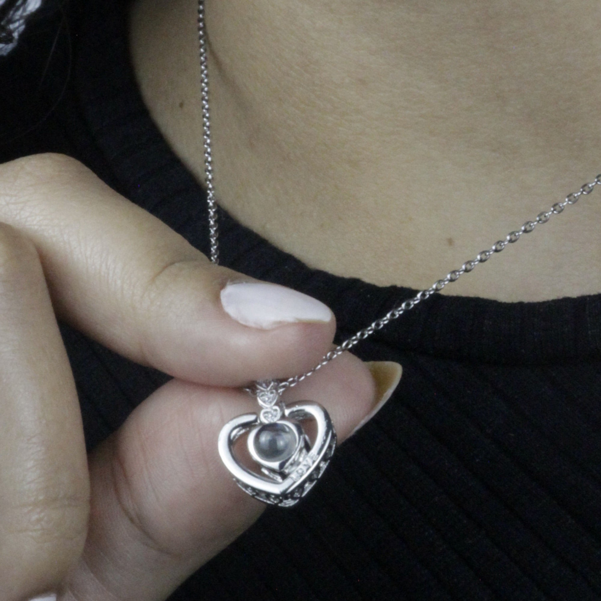 Colar_Eu_te_amo_dourado_em_formato_de_coracao_com_pedra_central_e_detalhes_cravejados_sendo_segurado_no_pescoco_2