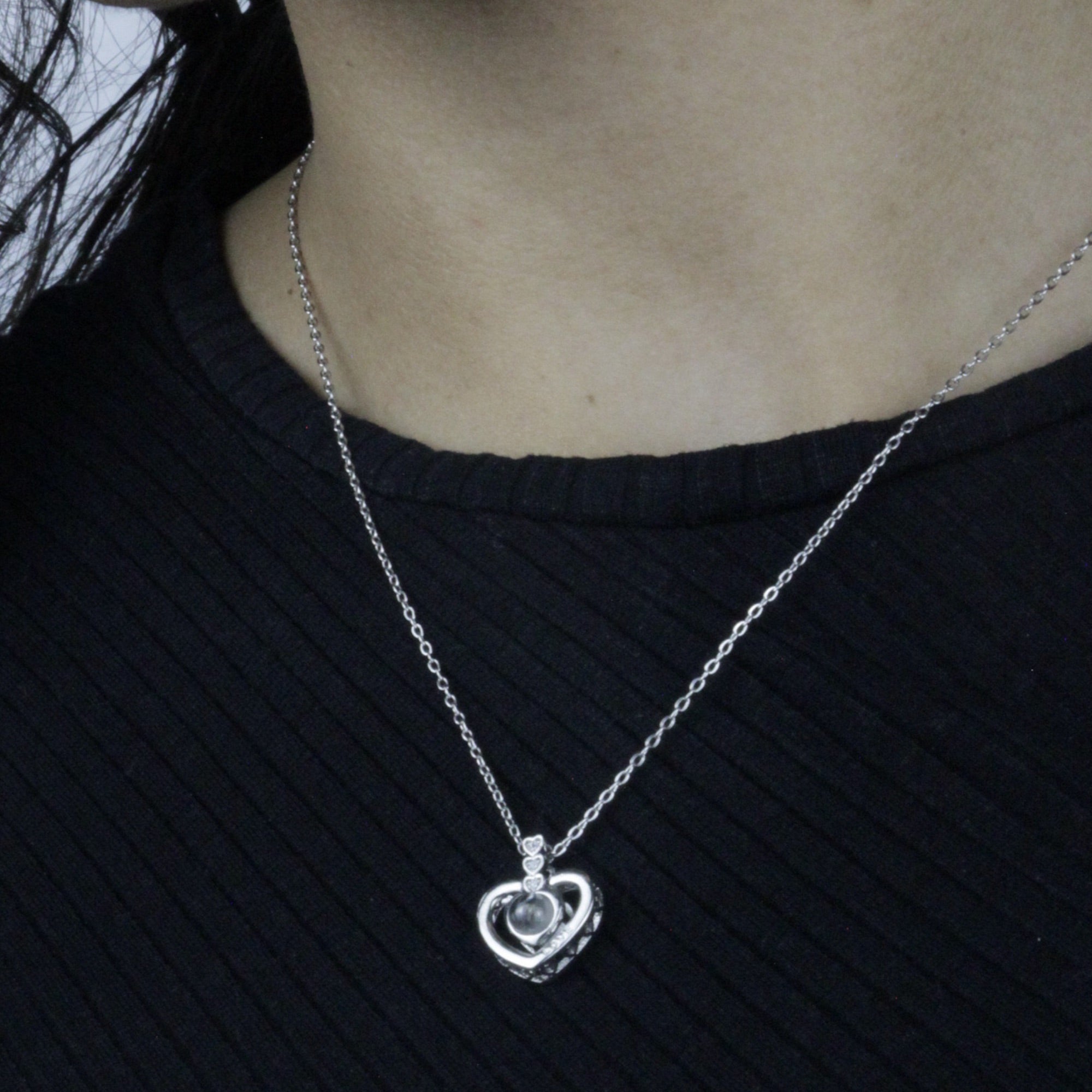 Colar_Eu_te_amo_prateado_sendo_usado_no_pescoco_com_pingente_em_formato_de_coracao_e_pedra_central_delicada