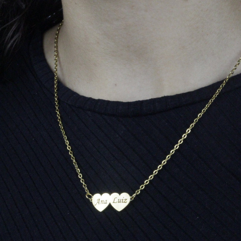 Colar_Meus_Coracoes_dourado_com_dois_nomes_gravados_modelo_usando_o_colar_sobre_blusa_preta
