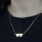 Colar_Meus_Coracoes_dourado_com_dois_nomes_gravados_modelo_usando_o_colar_sobre_blusa_preta