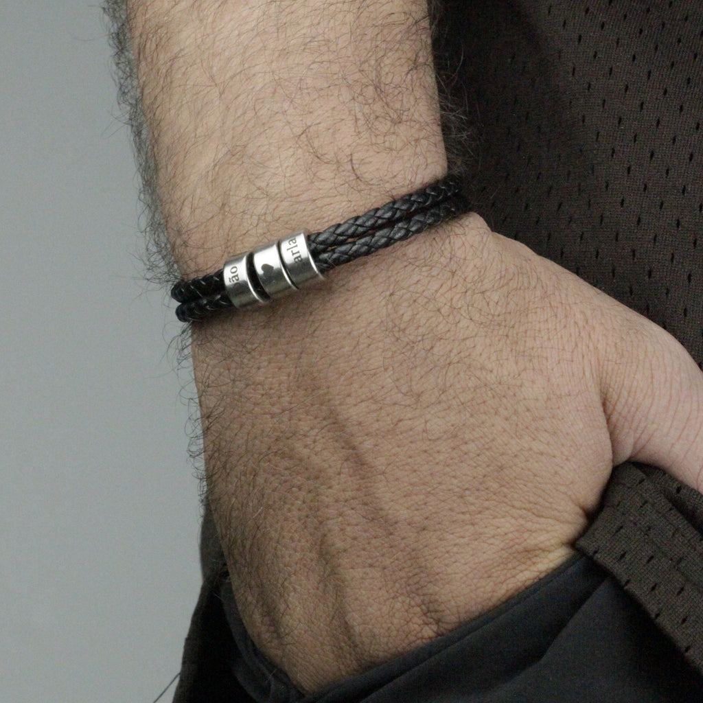 Pulseira_masculina_com_nomes_gravados_em_cilindros_metalicos_usada_no_pulso_em_composicao_casual