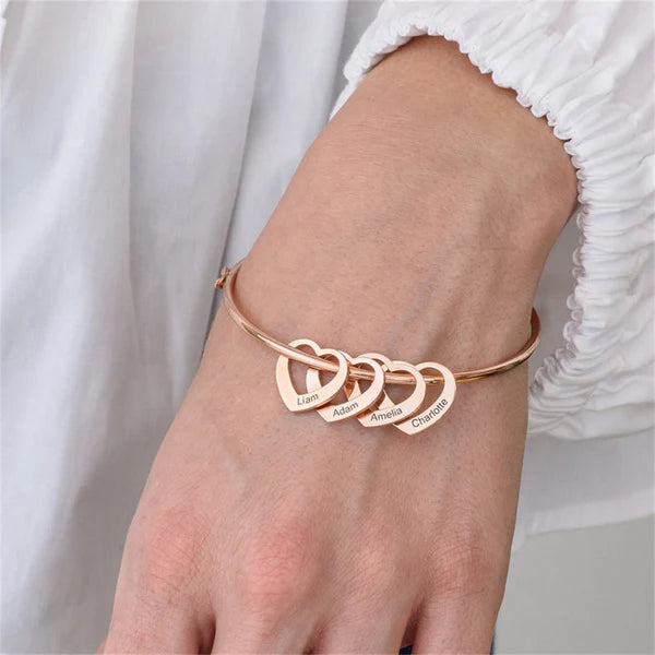 pulseira rígida personalizada rosé com quatro pingentes de coração gravados com nomes