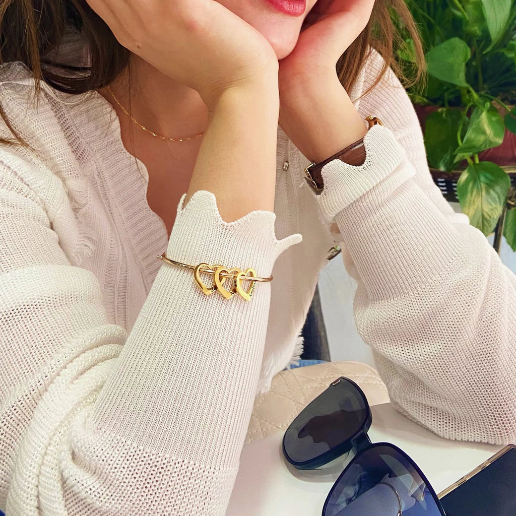 mulher usando pulseira rígida personalizada dourada com pingentes de coração