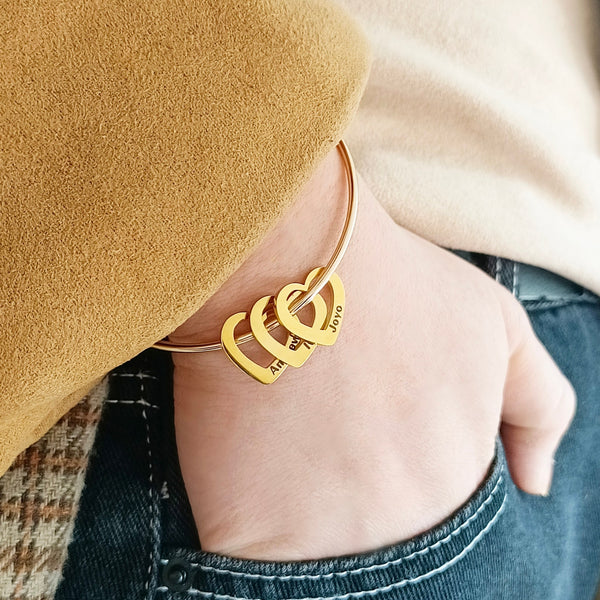 pulseira rígida personalizada dourada com pingentes de coração gravados no pulso